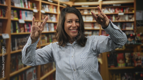 Foto Woman shows rock horns with both hands in a bookstore aisle inside a building; playful celebration moment
