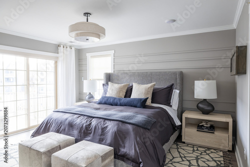 Modern Gray Bedroom with Dark Bedding, Upholstered Ottomans and Patterned Rug