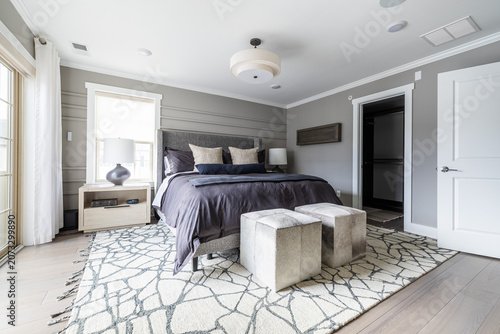 Modern Gray Bedroom with Dark Bedding, Upholstered Ottomans and Patterned Rug