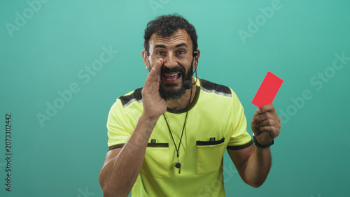 Bild auf Leinwand Man referee in neon shirt holds red card and whistle, hand cupped to mouth as if shouting, headset mic and beard visible in studio setting; discipline stern