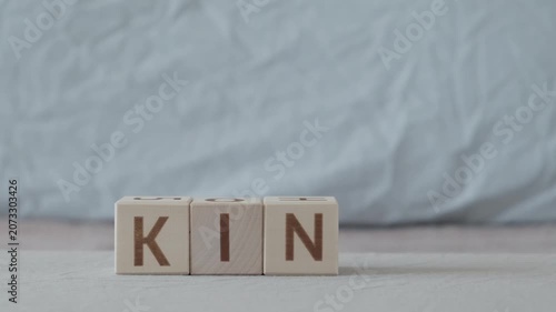 motivational word kind, laying out  by hand from letters on wooden cubes, slow motion
