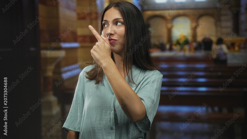 Fototapeta premium Woman smiles and points finger to side in a church aisle near altar and columns; faith reflection serenity devotion.