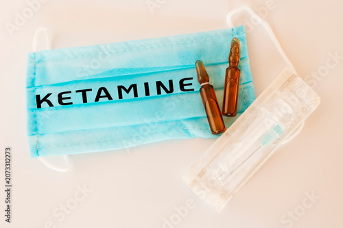 Medical mask displays ketamine vials and syringe on white background