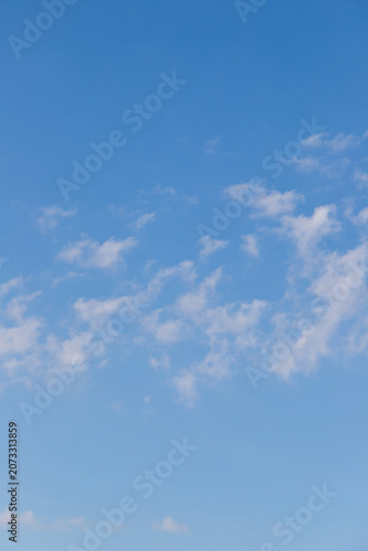 A clear blue sky filled with light, wispy clouds creating a calm, airy summer atmosphere perfect for backgrounds, nature and weather themes, peaceful design projects, or minimalist compositions.