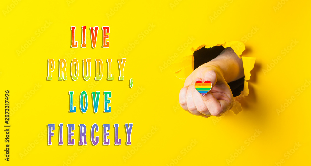 Fototapeta premium Hand Holding Rainbow Heart Through Yellow Paper with Inspirational Text