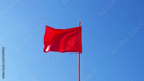 red flag flutters in wind against sky
