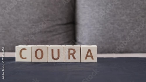 motivational word courage, laying out  by hand from letters on wooden cubes, slow motion
