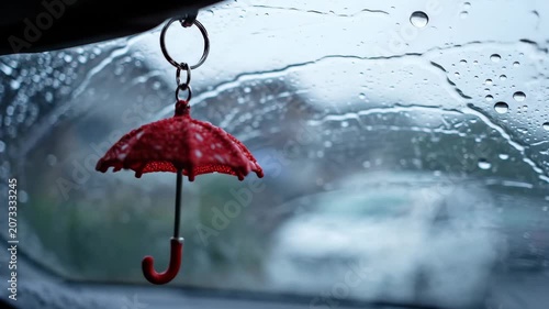 Red Umbrella Charm Hanging Inside Car During Heavy Rain.