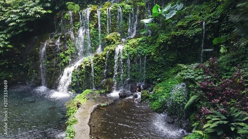Woman on scenic tropical waterfall surrounded by rainforest greenery