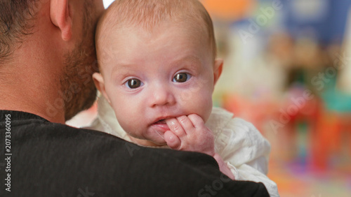 Εκτύπωση καμβά Baby girl held over adult shoulder with fingers in mouth and drool on chin in studio; quiet curiosity