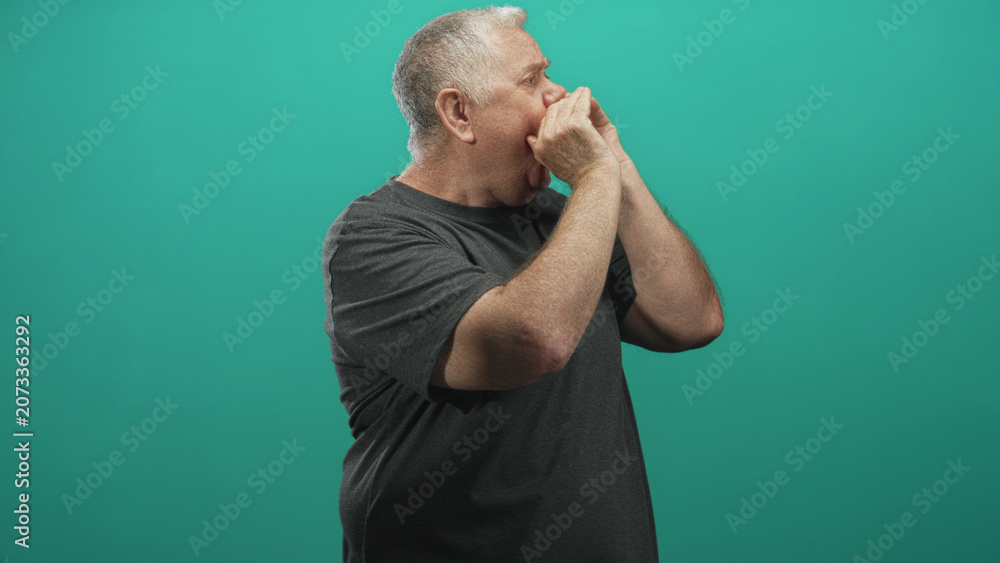 Fototapeta premium Senior man cupping hands to mouth shouting in studio with teal wall, visible bare hands and forearms in profile calling out to distance; communication urgency.