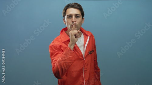 Tableau sur toile Man points finger at camera wearing orange prisoner jumpsuit with visible inmate number in studio; accusation