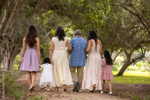 Family walking away on a path in a park during a sunny day