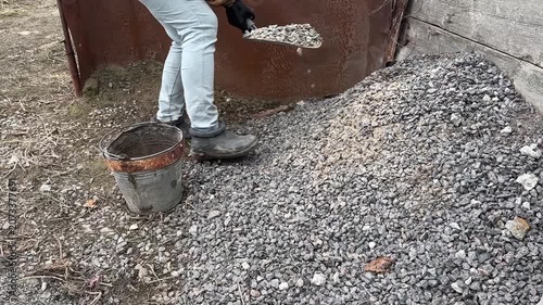 Worker Shoveling Gravel into Bucket in Outdoor Setting