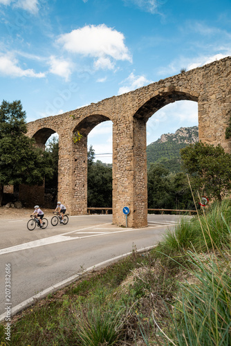 Vacation on Mallorca, cyclists pass under the old aqueduct