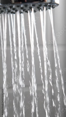 Close-up of water streaming from a shower head, creating a refreshing cascade, offering a cool and cleansing feeling