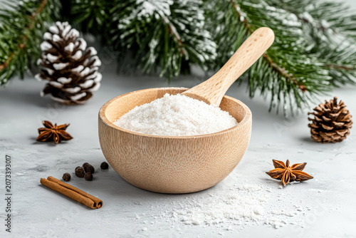 Wooden bowl filled with flour surrounded by cinnamon, star anise, and pine cones. Studio photography with a winter theme. Suitable for holiday recipes, food blogs, and seasonal marketing.