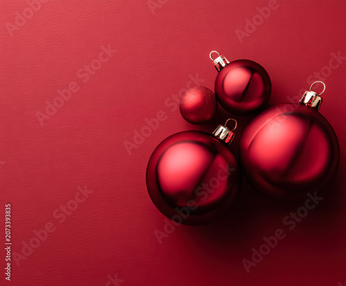 Red Christmas ornaments arranged on a textured red surface. Studio photography with a festive theme. Suitable for holiday greeting cards, seasonal promotions, and festive decor projects.