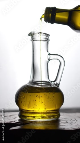 Slow motion of pouring organic olive oil into a glass bottle.