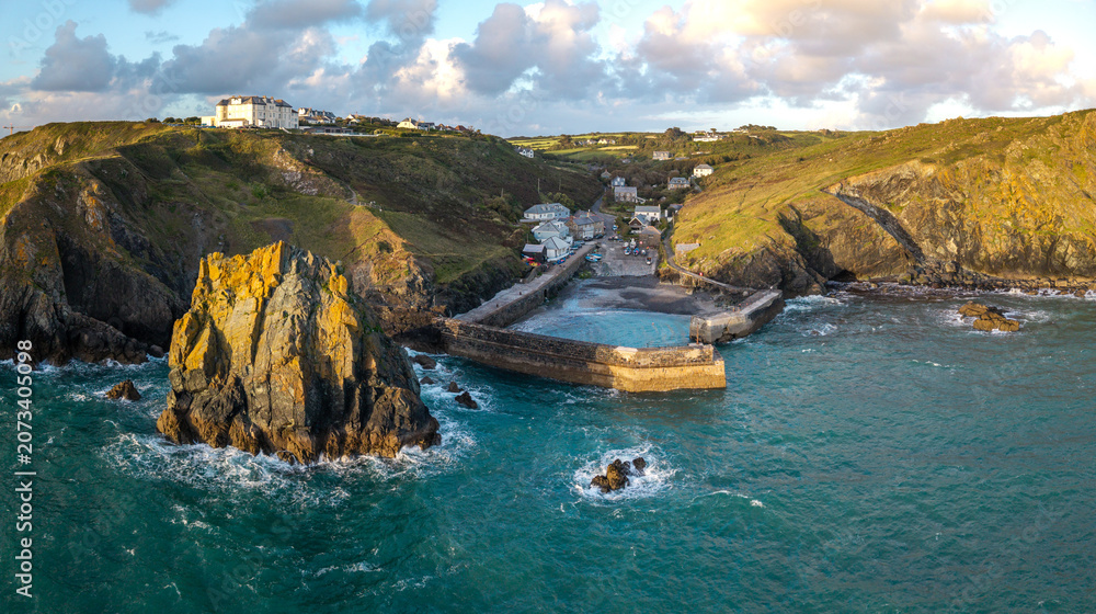 Fototapeta premium Aerial view from the sea of the Cornish fishing village of Mullion Cove and its historic harbour