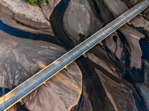 Aerial view of the Cloncurry River bridge crossing the dry, sandy riverbed with winding water channels in Cloncurry, Queensland, Australia.