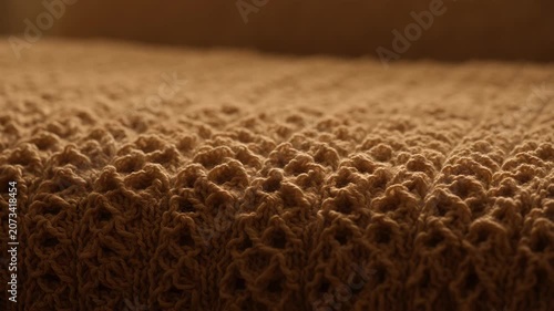 Close up of a warm beige knitted blanket texture with soft lighting