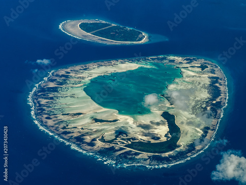 aerial landscape view of Saint-Joseph-Atoll,  with D'Arros Island behind as part of the Amirante Islands group in the territory of Seychelles, located in Indian Ocean - partly covered with clouds