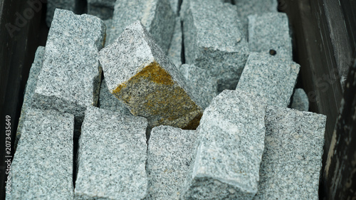 Natural grey granite cobblestones in a wooden crate close-up
