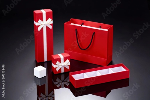Red Gift Boxes and Bag with White Ribbon on Black Reflective Surface