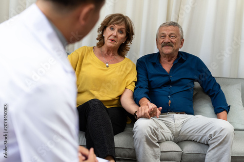 Photos Elderly couple sitting on a couch, holding hands, in conversation