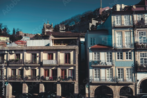 Quaint architecture showcases colorful balconies and charming details under bright sunlight in a vibrant neighborhood. The hills rise in the distance, blending nature with urban life