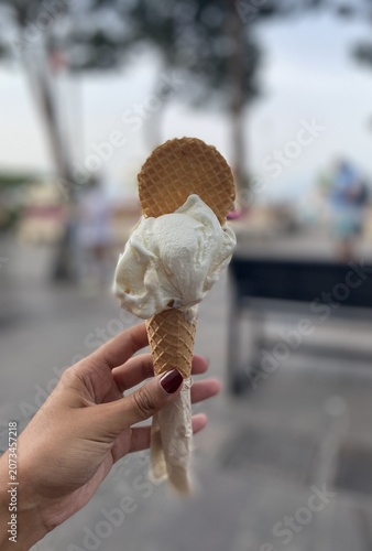 Cuadro en lienzo Gelado de baunilha em cone de bolacha segurado à mão, sobremesa refrescante com fundo desfocado em ambiente de verão