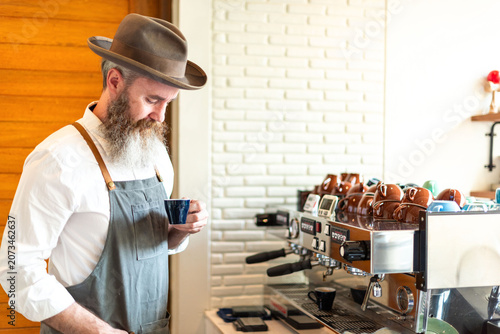 Quadro su tela Man with beard and hat making coffee at a cafe espresso machine.