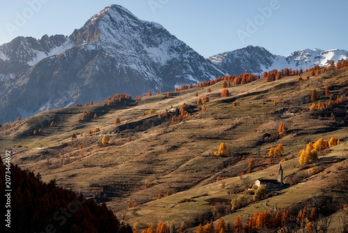 Fotografija Historic San Restituto church in Sauze di Cesana surrounded by autumn foliage wi