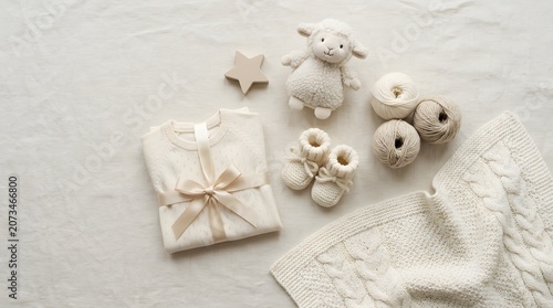 Neutral baby clothing and accessories laid out on a white background
