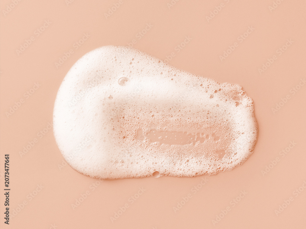 Fototapeta premium White skincare cleansing foam on light peach background