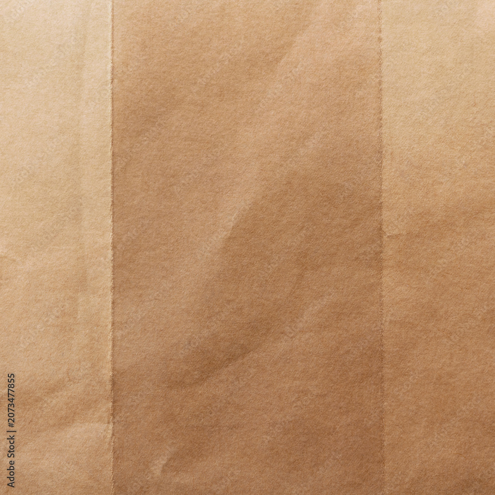 Fototapeta premium Close-up of a brown paper texture with subtle folds and soft shadows