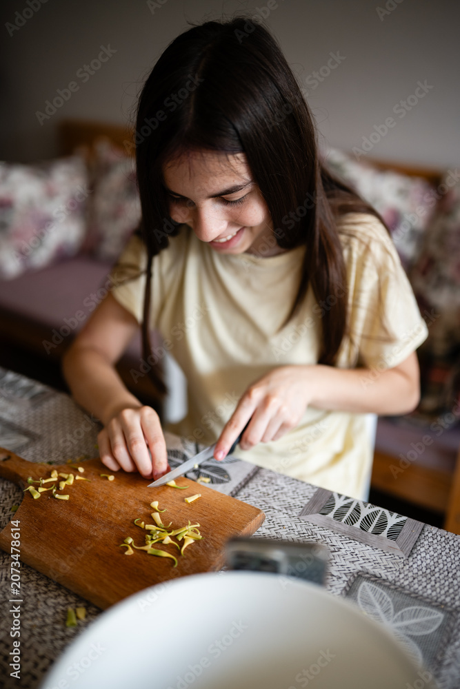 Fototapeta premium Smiling girl chopping vegetables for healthy cooking at home