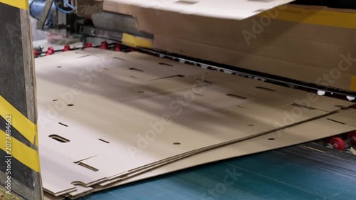 High speed conveyor system moving pre cut corrugated cardboard box templates inside a modern automated packaging plant.
