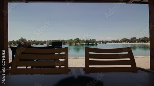 A laptop sits on a table at a lakeside cafe terrace overlooking Jarun Lake in Zagreb, Croatia.