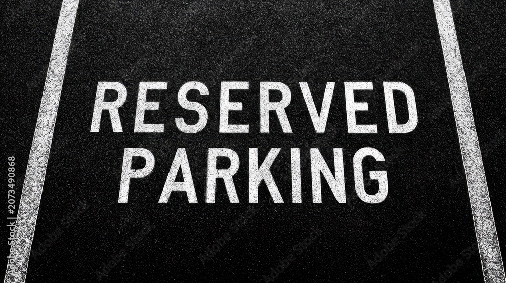 Fototapeta premium Reserved Parking Space Marked with White Stencil on Asphalt