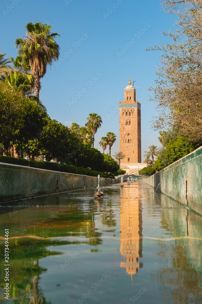 Fototapeta premium Le reflet dans une fontaine d'eau de la Koutoubia, mosquée historique de Marrakech au Maroc. Le format est vertical.