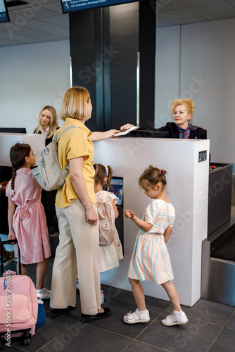 Family checks in at airport with children and staff assisting during busy travel time