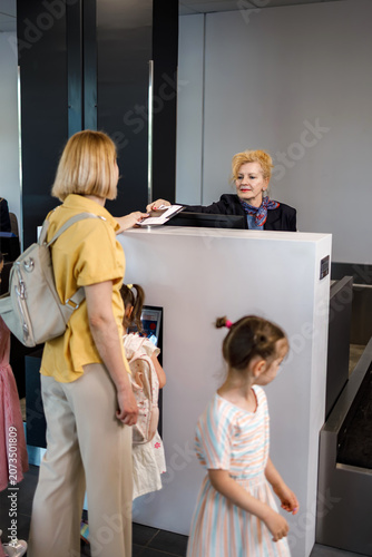 Travelers check in at the airport with staff at the reception desk during busy morning hours