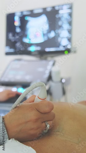 Obstetrician using an ultrasound transducer on a pregnant woman's belly in a clinic