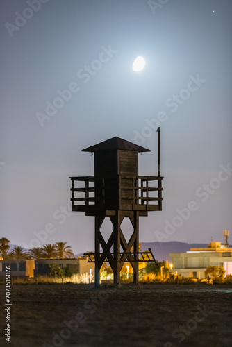 Illuminated Coastal Surveillance Tower Under Full Moon Night Sky