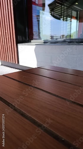 A child's hands offer a piece of bread to a sparrow on a café table; the sparrow pecked at it and flew away.