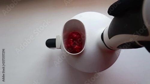 A blender is blending strawberries on the countertop.