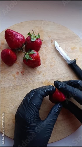 Fresh strawberries being prepared on a wooden cutting board  