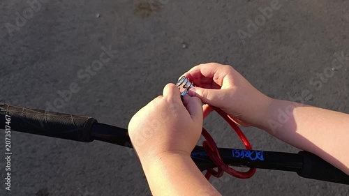 Child fastening a red bungee cord to a scooter outdoors  